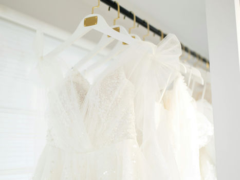rail of wedding dresses in a simple satin wedding dress in a calm bridal outlet boutique setting
