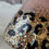 Thumbnail: Close-up of glittery leopard print detail on a vintage blush with gold tumbler with black spots and holographic sparkle.