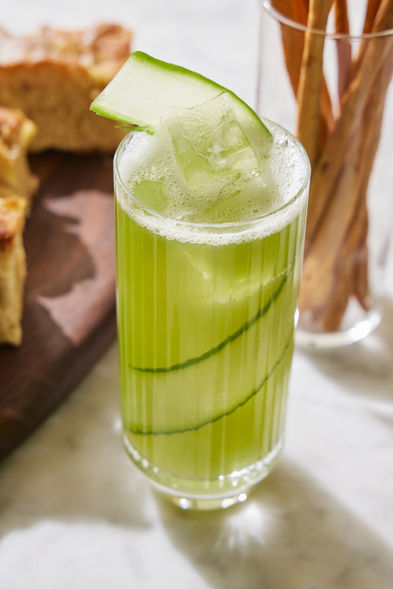 Refreshing green cocktail with cucumber slices and bread, perfect summer drink.