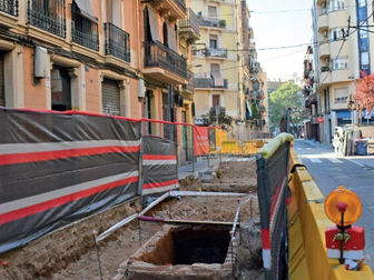 Carrers de Barcelona amb obres al centre; tanques grogues i taronja delimiten la zona. Edificis residencials als costats. Sensació de tranquil·litat.