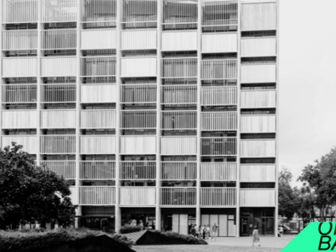 Edifici de vidre modern amb finestres grans. Persones caminen pel carrer. Vegetació al voltant. Text "OPEN BARRI" en un angle inferior.