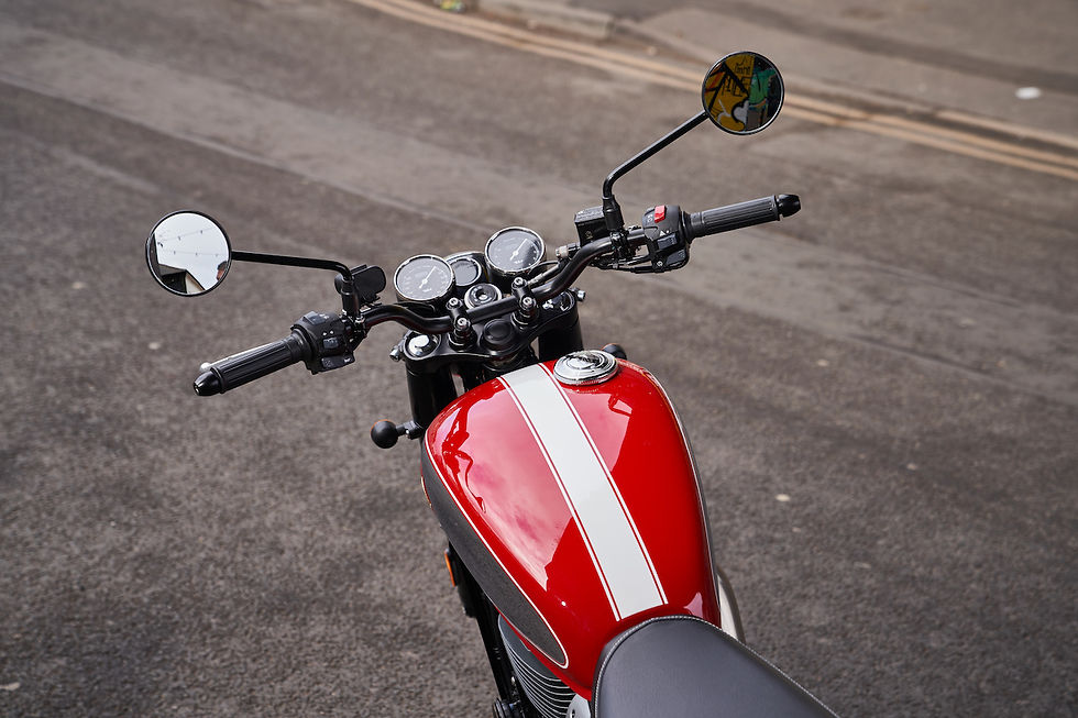 Red motorcycle with white racing stripe parked on asphalt, seen from above with handlebars and mirrors visible.