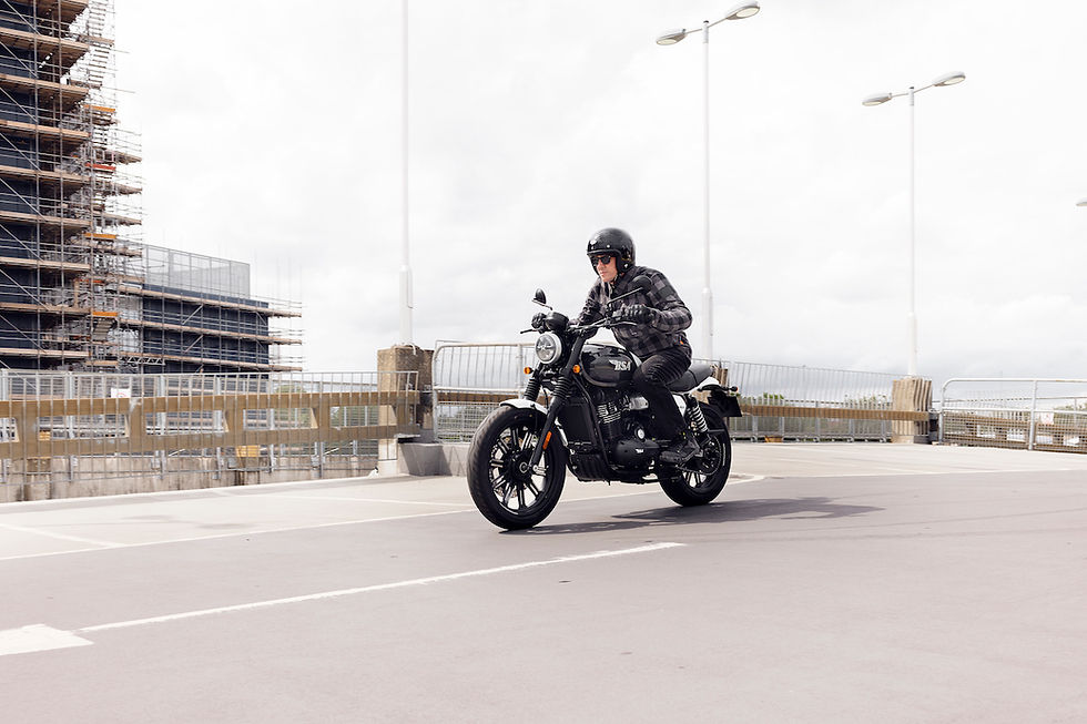 Man with an open face helmet riding a BSA Bantam 350 on a parking garage.