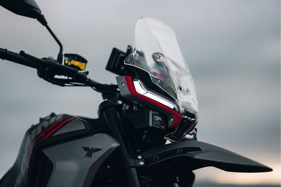 Close-up of a sleek black and red motorcycle with a clear windshield against a gray sky at dusk.