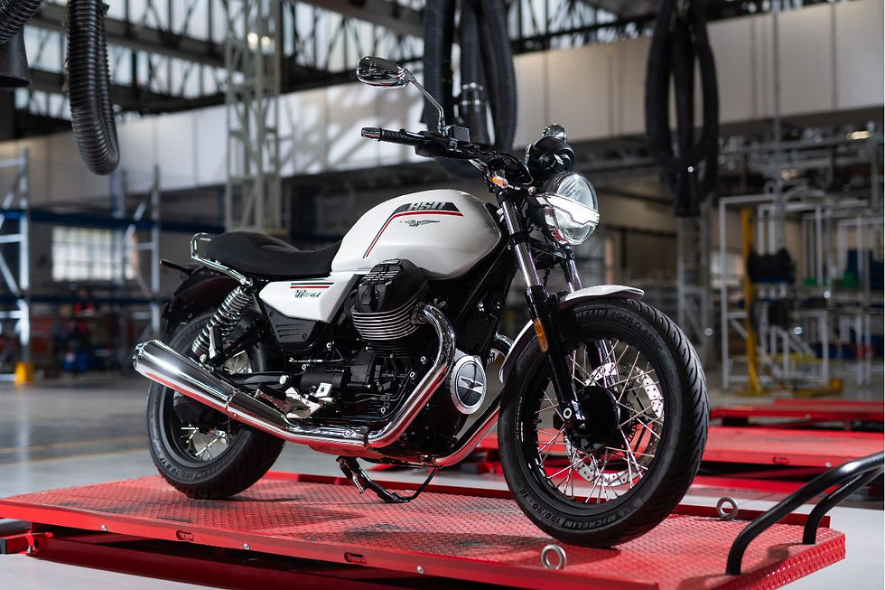 White-and-black BMW 850 motorcycle on a red platform in an industrial garage, with chrome exhaust and a bold, polished look.
