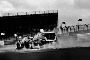 Two race cars speeding on track, black and white