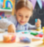 Smiling girl playing with colorful clay at preschool
