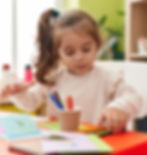 Young girl coloring with crayons at her desk