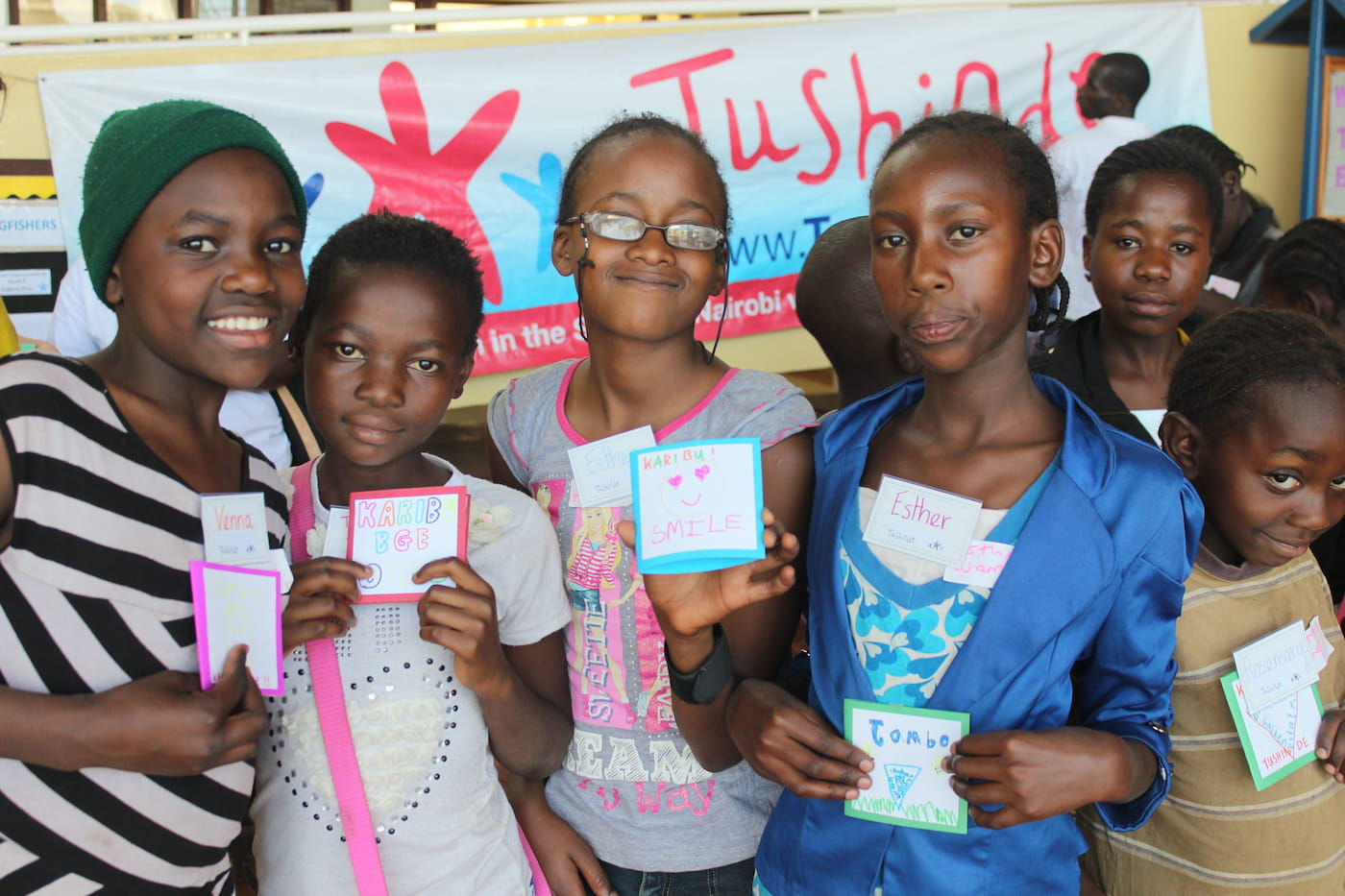 Smiling girls at Tushinde event hold handmade cards
