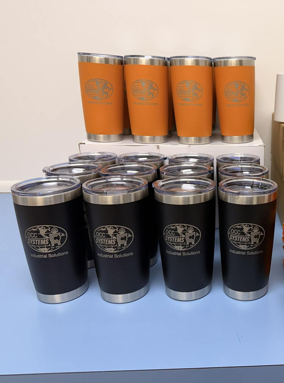 Thumbnail: Several black and orange tumblers with etched company logos.