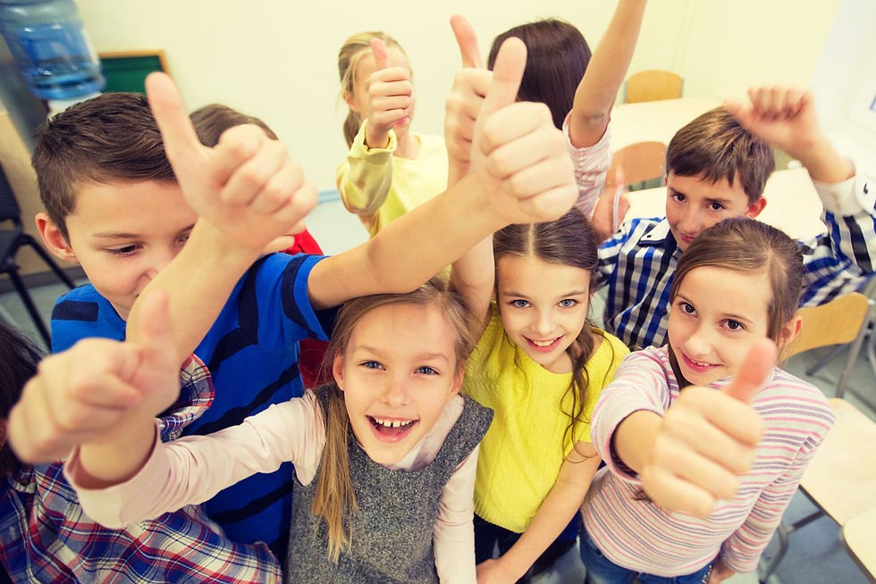 Happy primary school children in a classroom giving thumbs up — building confidence, teamwork, and a positive learning environment.