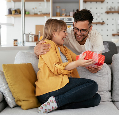 woman receiving gifts from man. hugging on couch.