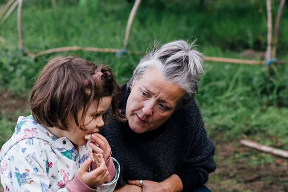 Woman crouching down next to a SEND child at Wild Embers.