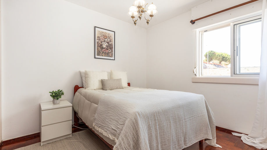 Quarto com cama de casal, decorado com colcha neutra e almofadas claras. Armário embutido em madeira escura e um quadro na parede adicionam um toque clássico ao espaço, organizado pela Little Details Home Staging para um ambiente acolhedor e harmonioso.