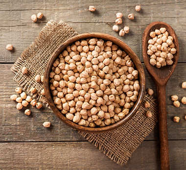 Wooden bowl and wooden spoon full of chickpeas on wooden background. Top view..jpg