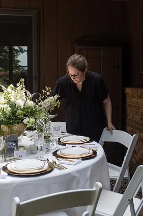 Certified Wedding Planner Betsy Baker preparing a white and gold guest table at a Private Estate Wedding
