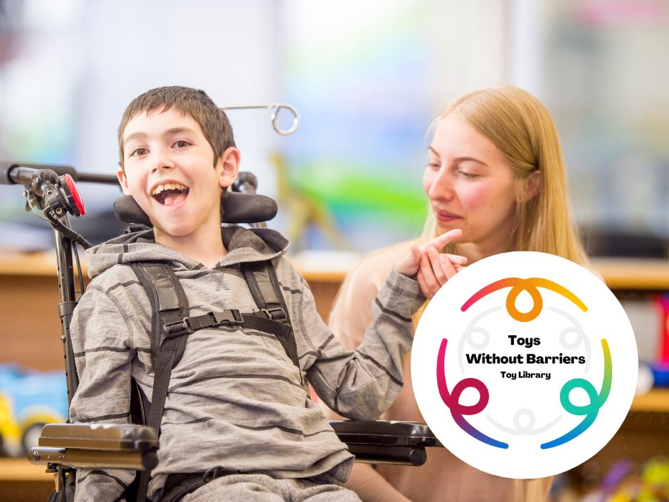 A smiling young boy using a wheelchair sits beside a woman who is gently holding his hand. Both appear happy and engaged. A circular “Toys Without Barriers Toy Library” logo is placed in the bottom right corner.