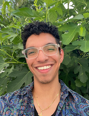 Joe Colangelo, the artist stands, smiling in front of lush greenery