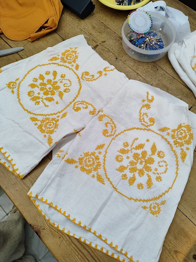 sewn shorts on a table next to a bowl with a magnet and pins