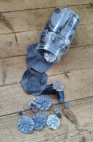 plstic bottle with fabric circles yoyos and buttons on a table