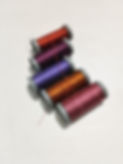 5 spools of hand sewing thread laid out on a table