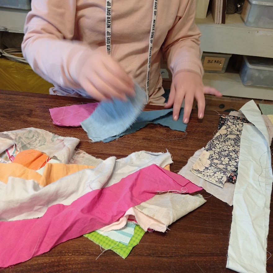 girl choosing fabric strips for a sewing project