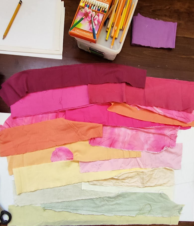 fabrics laid ount on a table in a sunrise design nect to paper and coloring pencils