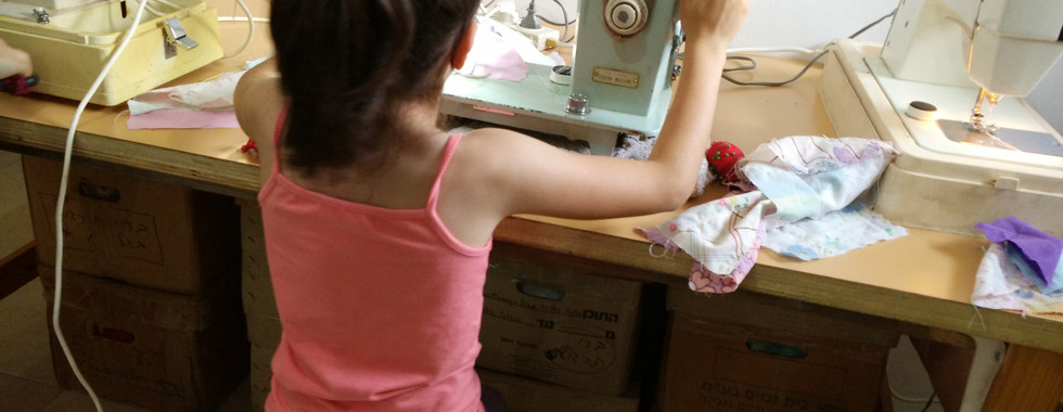 ילדה קטנה תופרת על מכונת תפירה