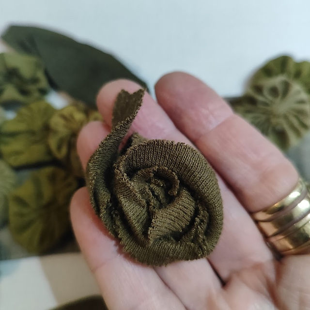 fabric rose in camo colors resting on fingers