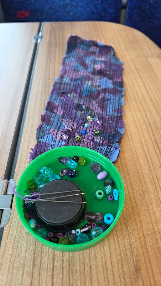 twilight fabric bottle cap beads needles anf magnet on a table in the train