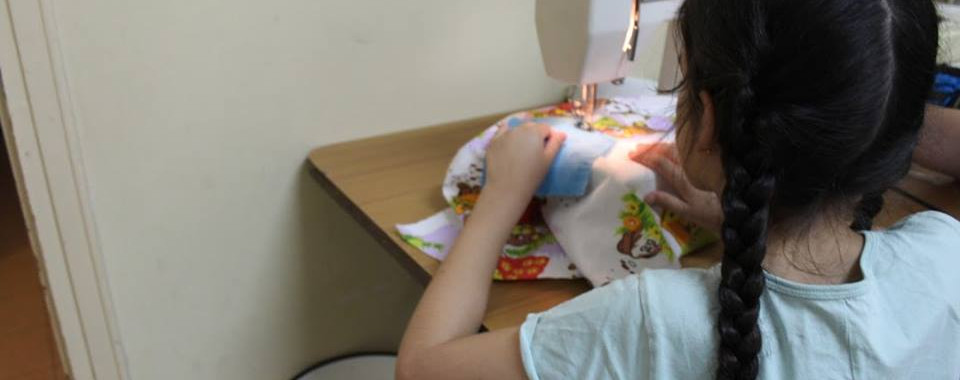 girl with black hair sewing on sewing machine