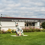 the front side of a building with a wolf statue in the lawn
