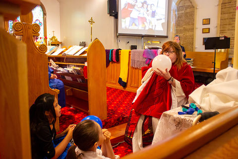 The Rev. Jann leading the Kids' Time during a Sunday service. Blowing up a balloon.