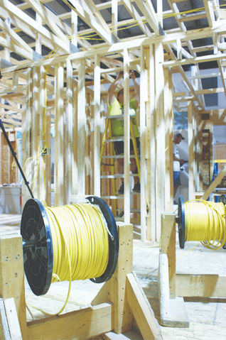 Electrical wiring and electricians working on a prefab home.