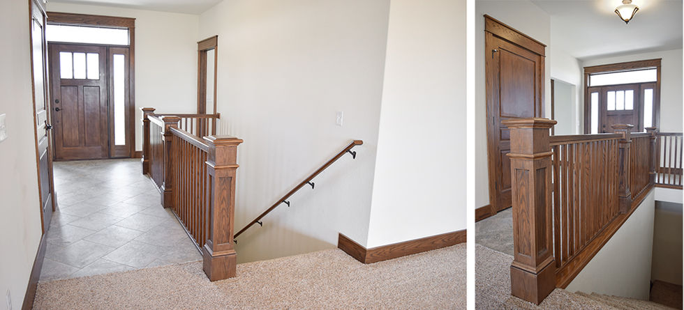 Wood craftsman deluxe railing near front door beside stairs to basement.