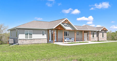 Home with gray siding, custom masonry, wood beams, lots of windows, and a porch area. Built by Wardcraft in KS and NE.