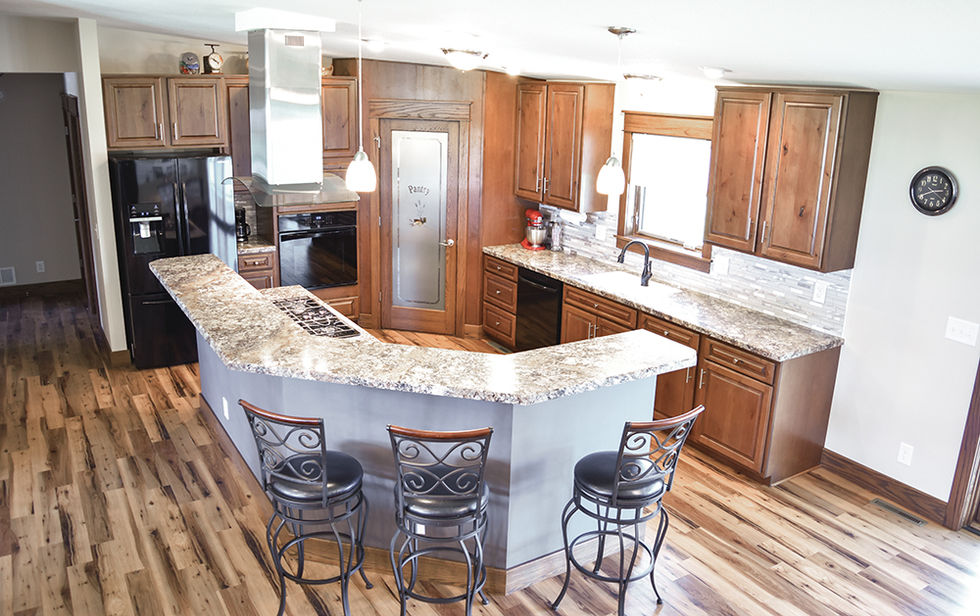 Modern kitchen with angled island and wood wrapped pantry in corner.