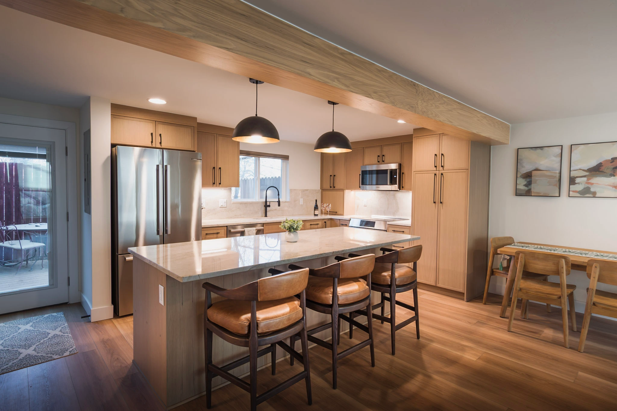 Bright modern kitchen with large island, light wood cabinets, and dining space.