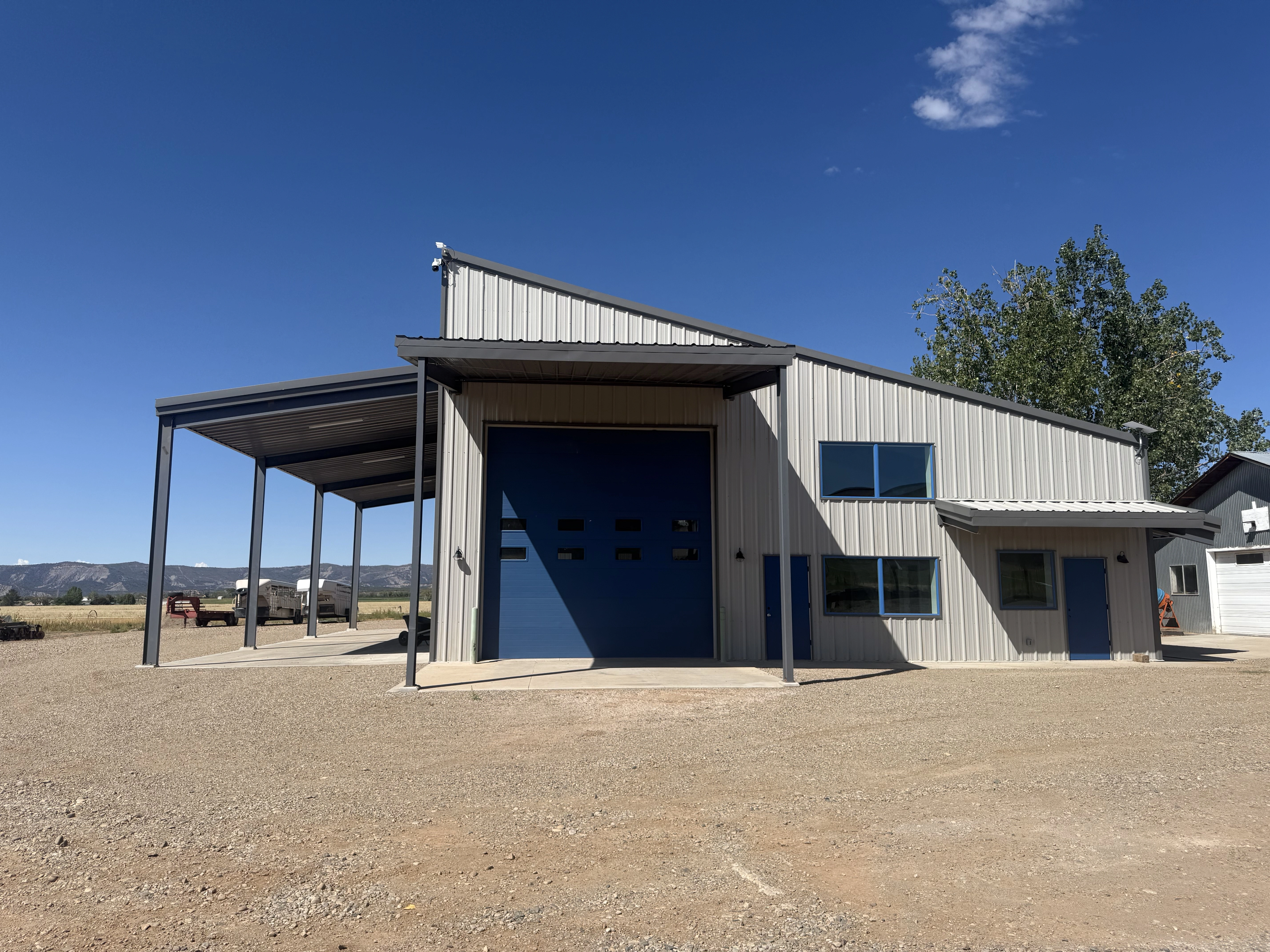 Grey metal storage building with large blue garage door