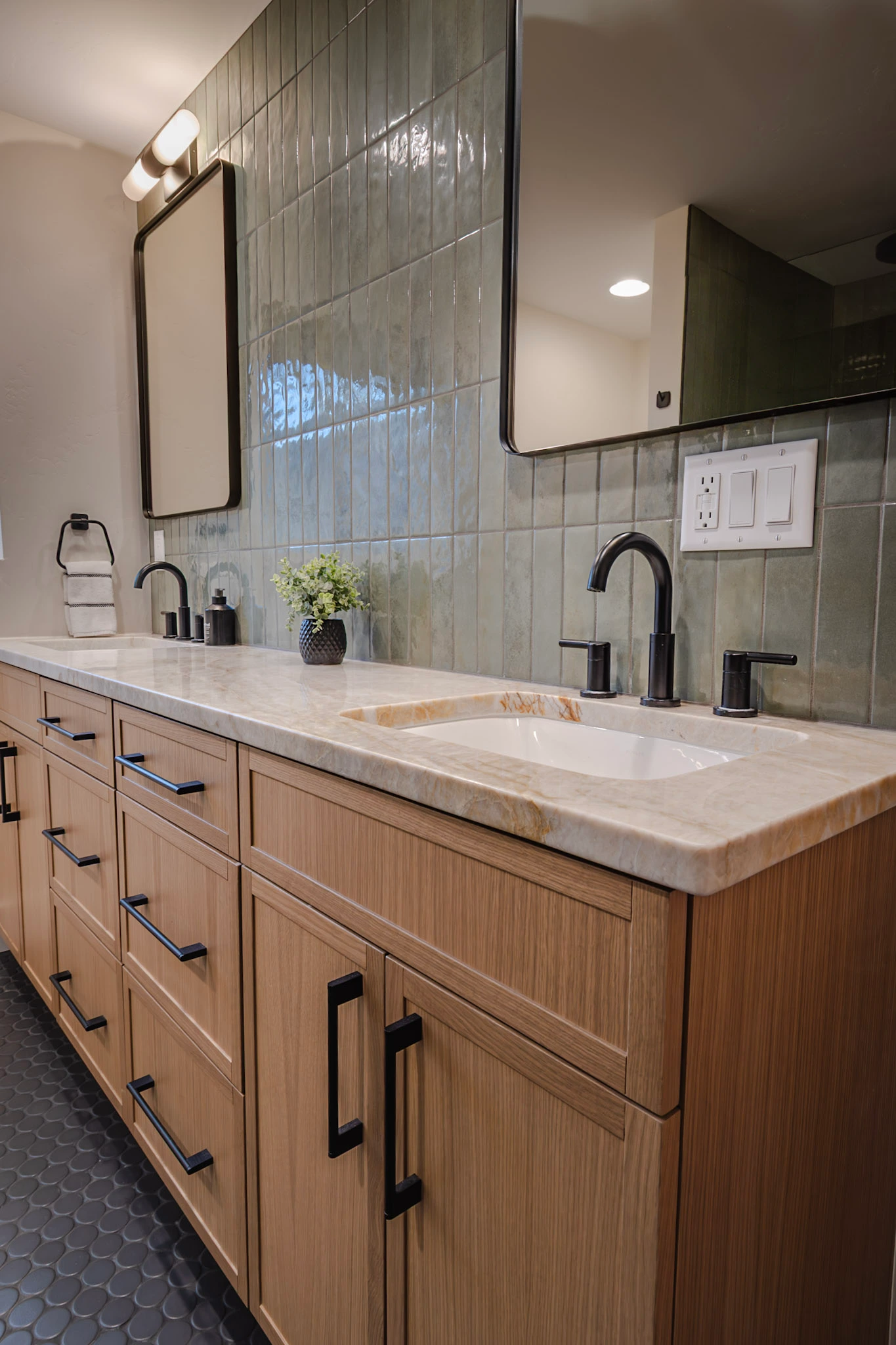 Double vanity with wood cabinets, white counter, green tile wall