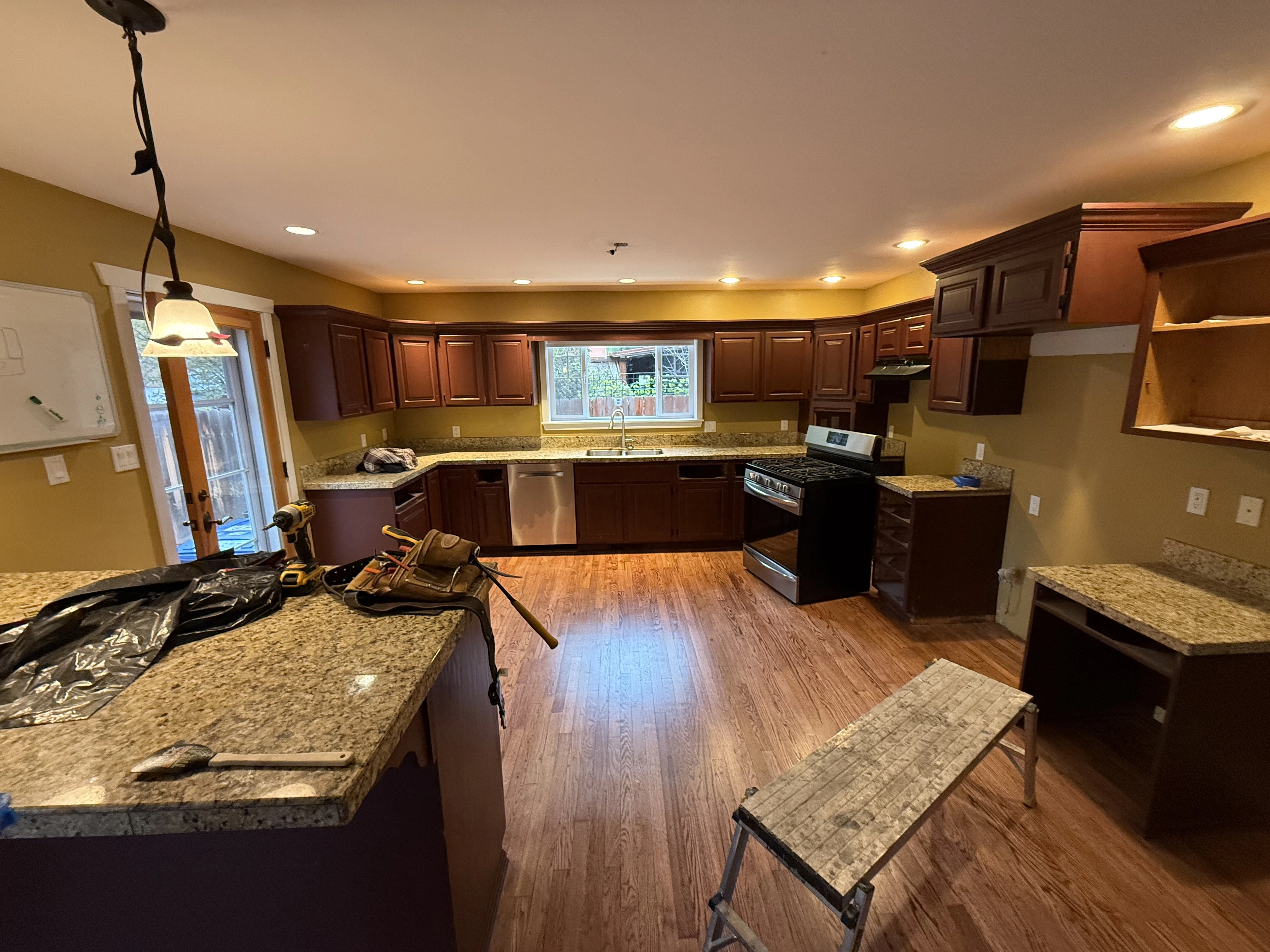 Kitchen with dark cabinets, granite counters, wood floor