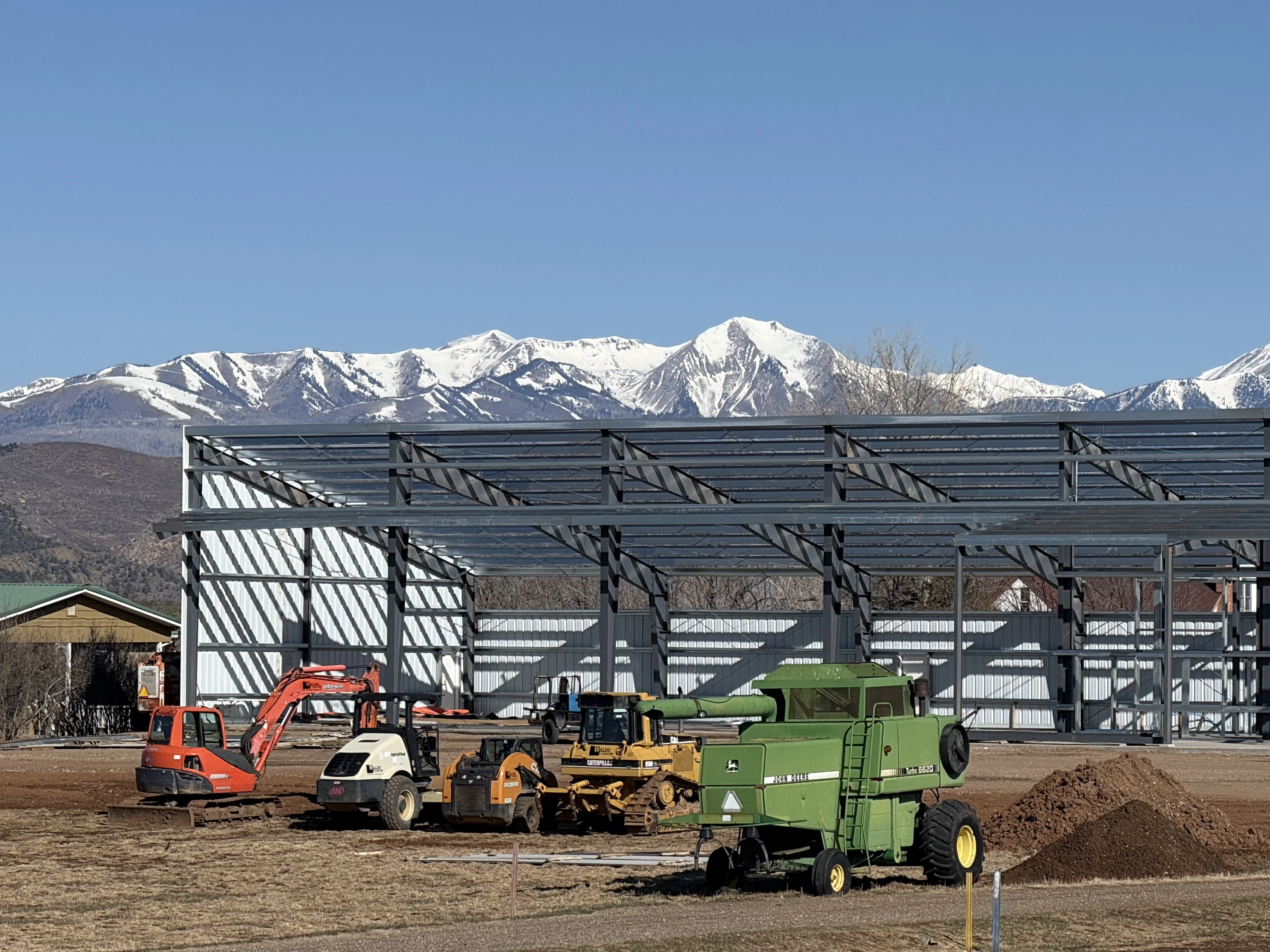 Construction of a metal storage building with farm equipment and mountains
