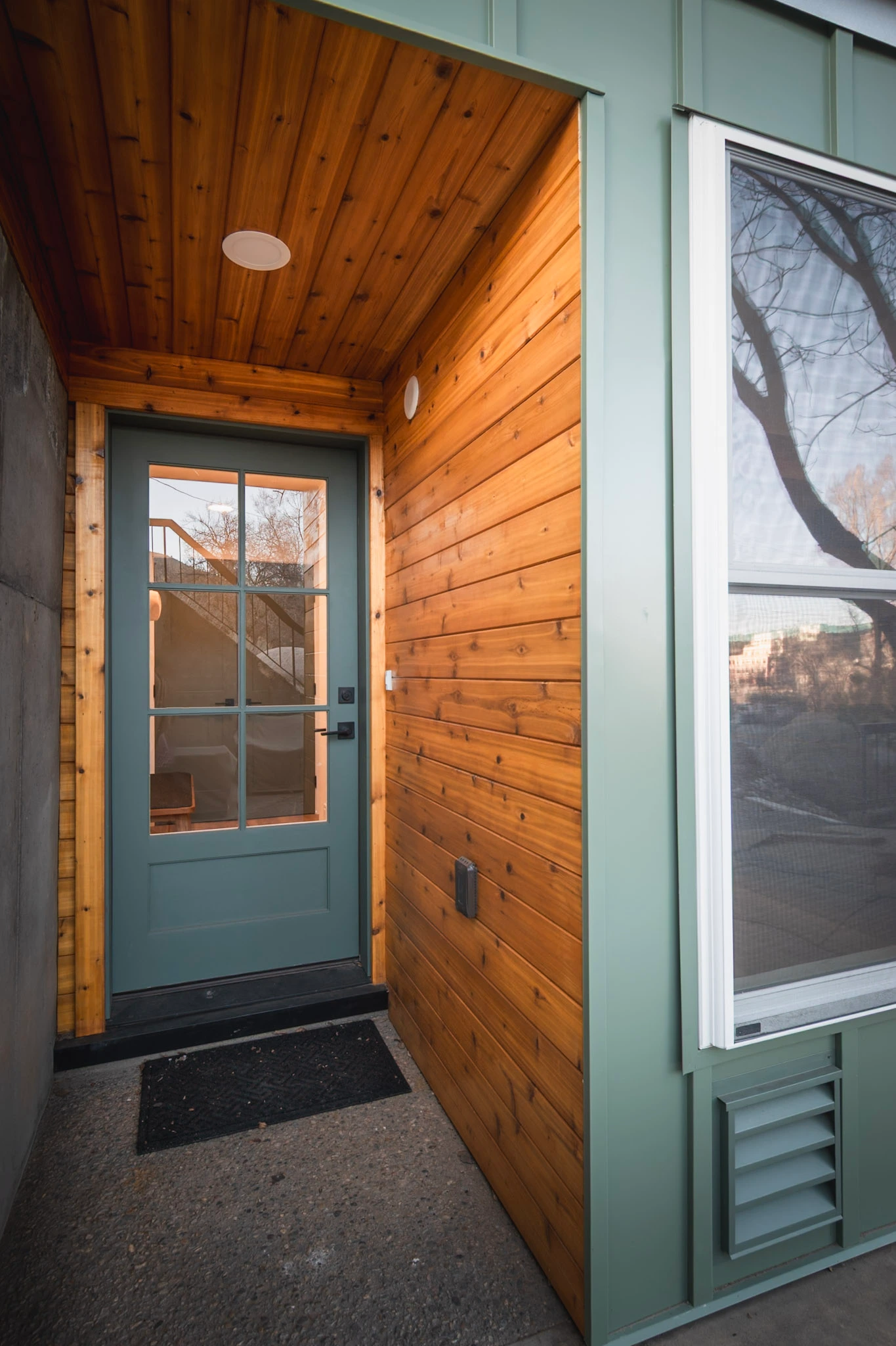 Building entrance with teal door and wood siding