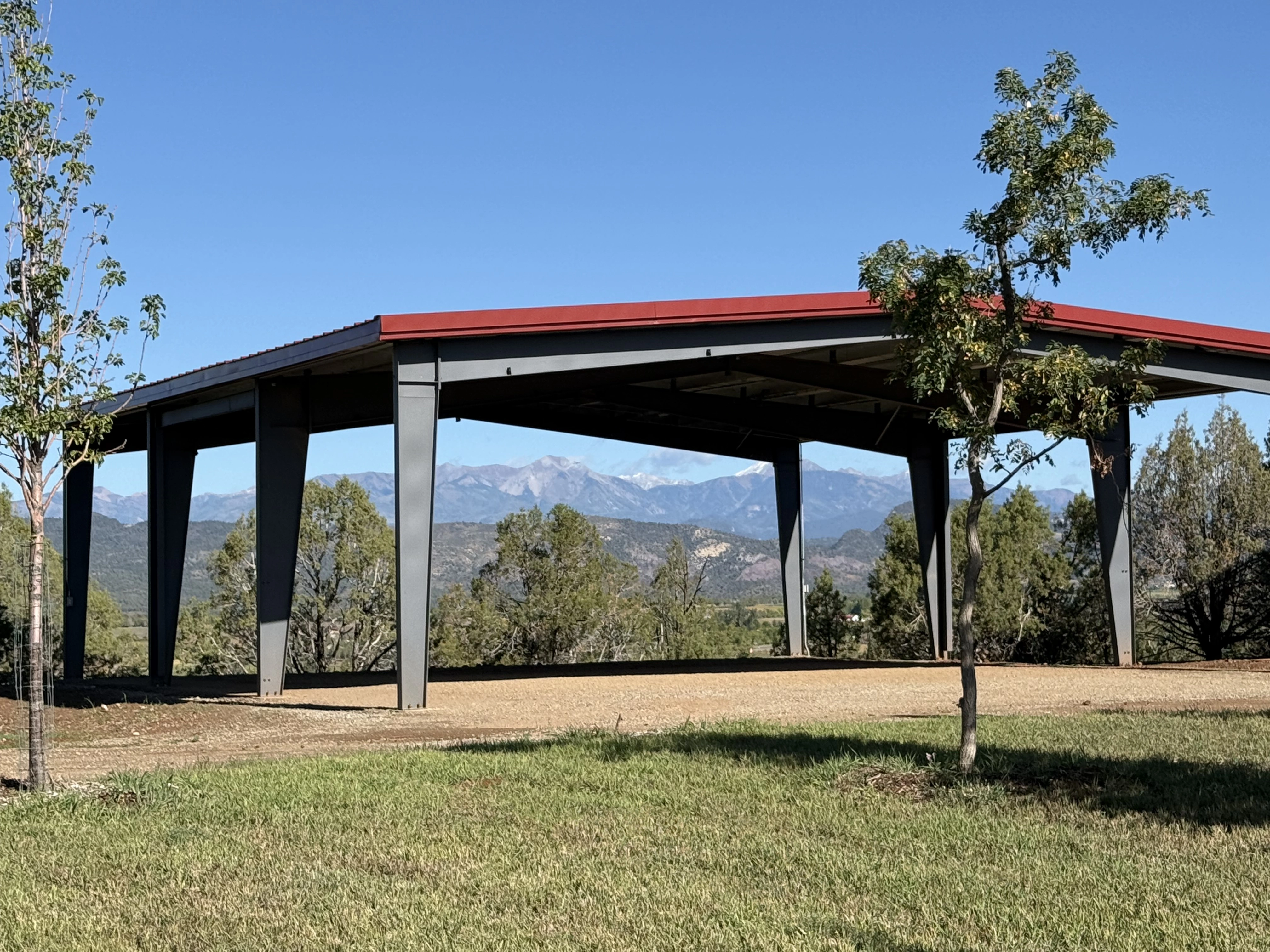 Open-sided storage building with red roof, mountains