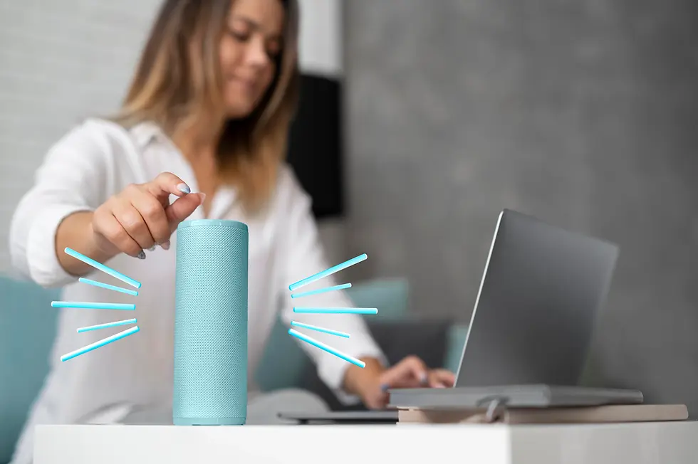 Woman in white shirt uses a turquoise smart speaker on a white table, with laptop open nearby. Modern home setting, relaxed mood.