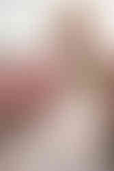 Woman in a hat and long, beige dress holding a bouquet of tulips in tulip field