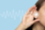 A woman puts her hand to her ear and listens, isolated on a blue background with sound wav