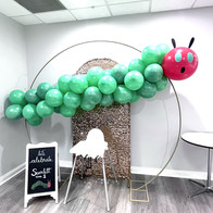 Green balloons and a red face to make up a Hungry Caterpillar balloon arch.
