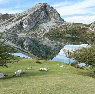 Lake Enol reflecting the surrounding mountains and sky.