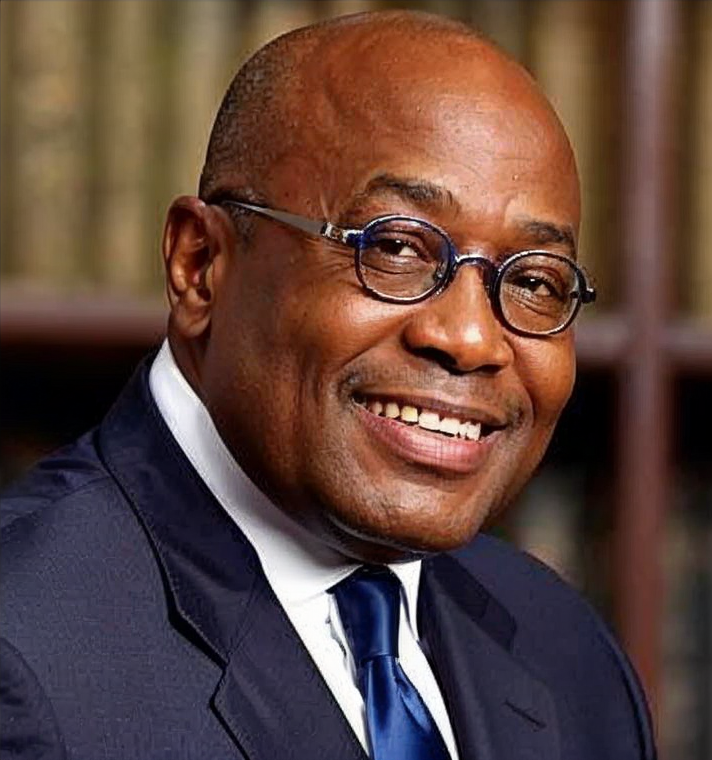 Portrait of Nana Akufo-Addo, President of Ghana, wearing a suit and glasses, smiling slightly with a flag in the background
